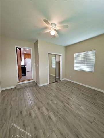 a view of an empty room with window and wooden floor