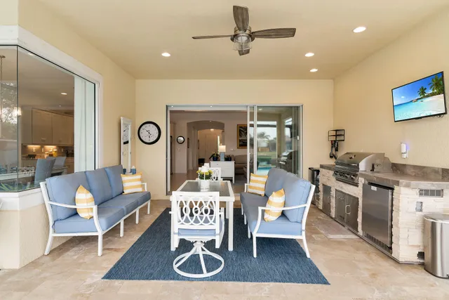 a living room with furniture a floor to ceiling window and a kitchen view