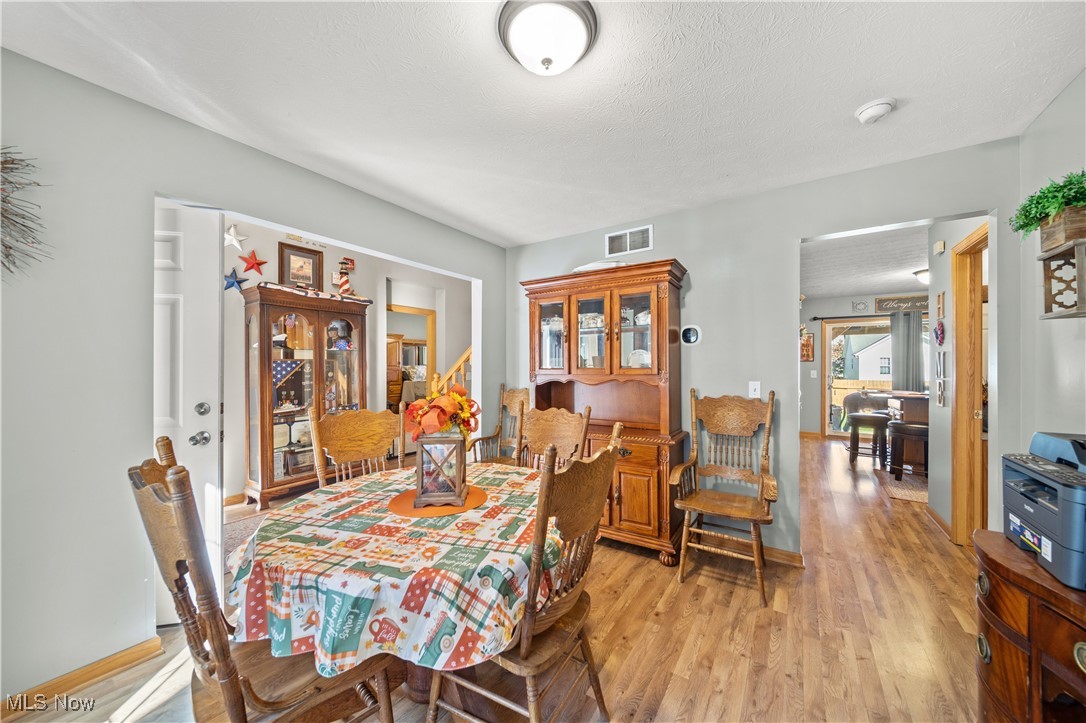 Dining area with light hardwood / wood-style flooring and a textured ceiling