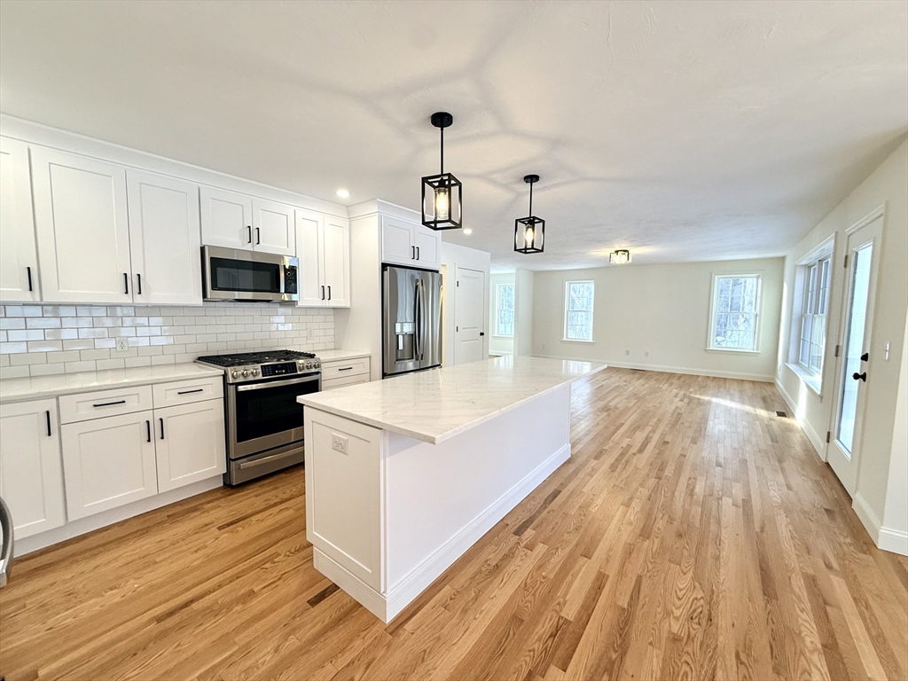 28 Forest Hill Drive Rutland, MA 01543 - Photo 4 of 23 a large kitchen with kitchen island a stove top oven a sink dishwasher a dining table and chairs with wooden floor