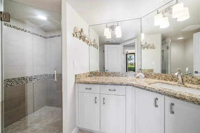 a bathroom with a granite countertop sink a mirror and shower
