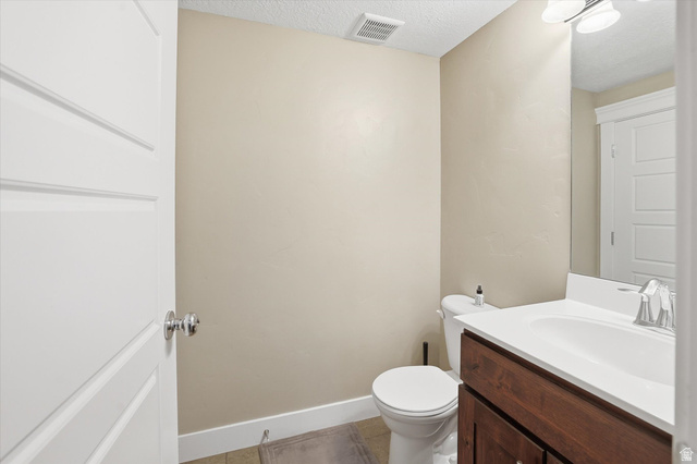 1024 South 270 West Logan, UT 84321 - Photo 12 of 37 Half bathroom with vanity, a textured ceiling, and light tile patterned flooring