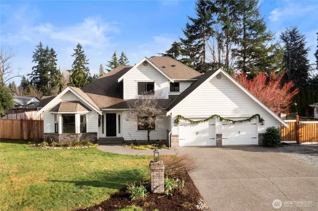 a view of a white house next to a yard with large trees