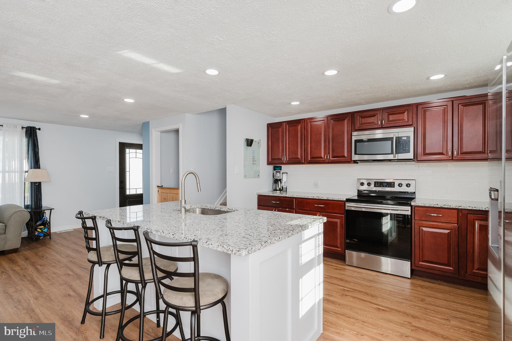 930 Edmund Street Aberdeen, MD 21001 - Photo 12 of 61 a kitchen with stainless steel appliances granite countertop a stove top oven a sink a refrigerator and a granite counter tops with wooden floors