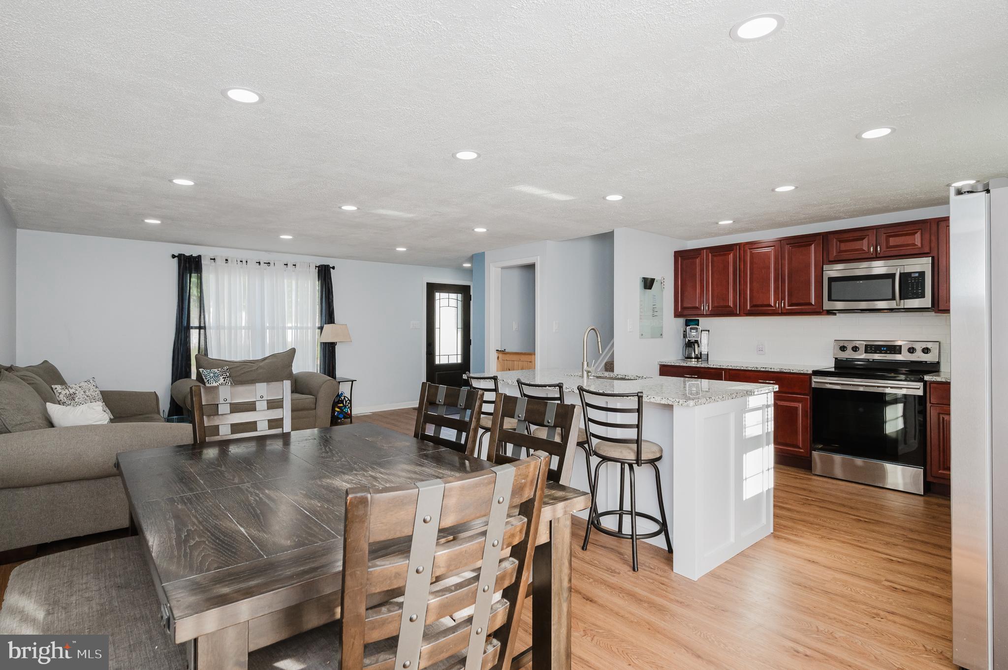 930 Edmund Street Aberdeen, MD 21001 - Photo 18 of 61 a large kitchen with stainless steel appliances granite countertop a stove a sink a refrigerator and a dining table with wooden floor