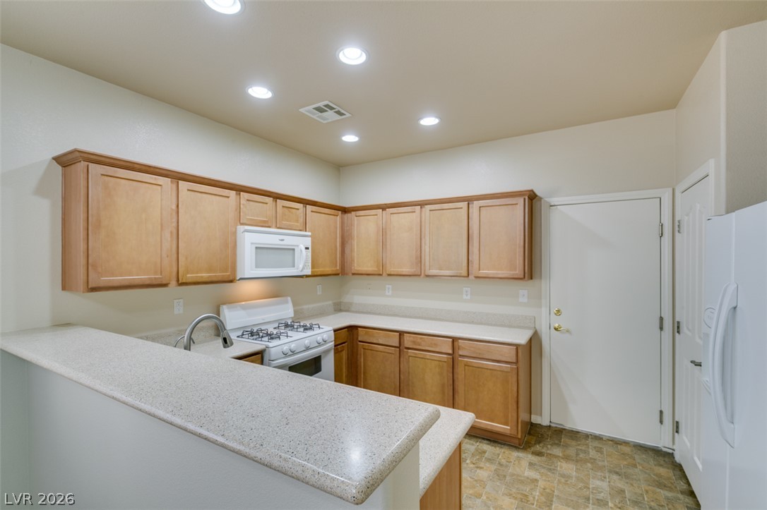 8937 Caledon Ridge Court Las Vegas, NV 89149 - Photo 22 of 43 A functional kitchen boasts light wood cabinetry and resilient tile flooring, ready for culinary endeavors.