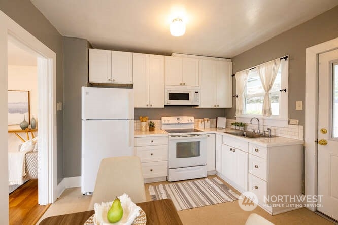 9340 45th Avenue Southwest Seattle, WA 98136 - Photo 15 of 33 a kitchen with white cabinets a stove a sink and a refrigerator