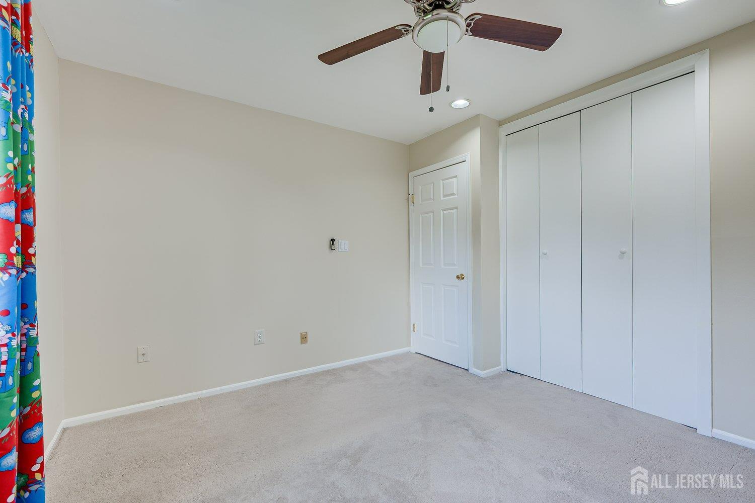 7 Lily Court Edison, NJ 08820 - Photo 21 of 32 an empty room with a ceiling fan and carpet