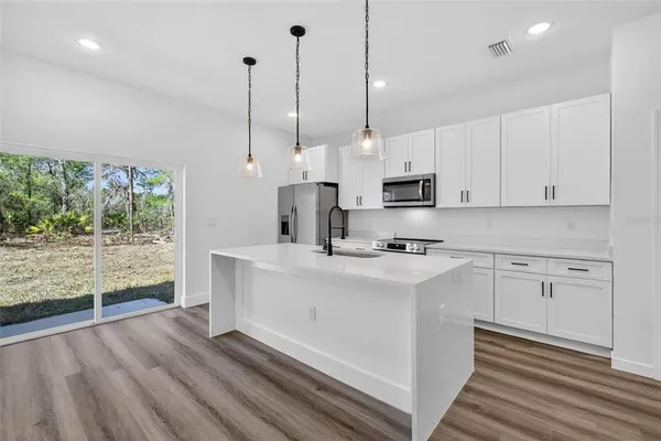 a kitchen with stainless steel appliances granite countertop a sink a stove and a wooden floors