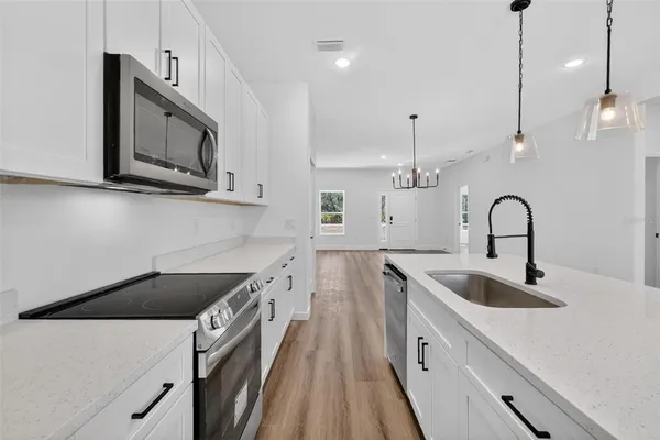 a kitchen with stainless steel appliances granite countertop a sink a microwave a stove and a wooden floors
