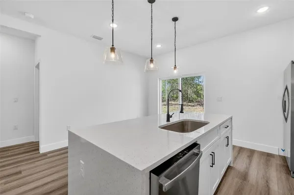 a kitchen with a sink a window and wooden floor