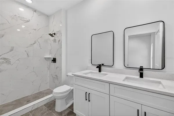 a bathroom with a toilet a sink a mirror and shower