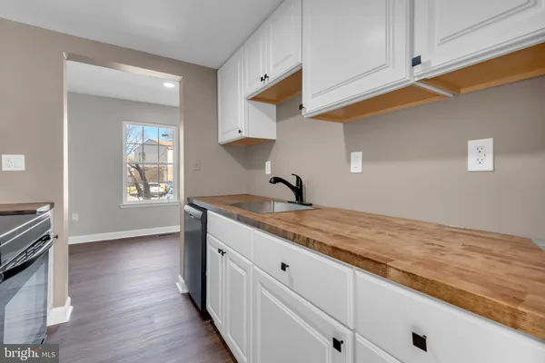 a hallway with stainless steel appliances granite countertop a sink and wooden floor