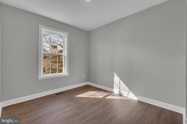an empty room with wooden floor and window