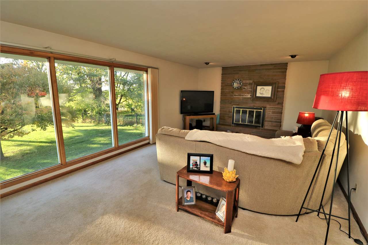 3777 Wheeler Road Cherry Valley, IL 61016 - Photo 3 of 21 a living room with furniture a flat screen tv and a floor to ceiling window