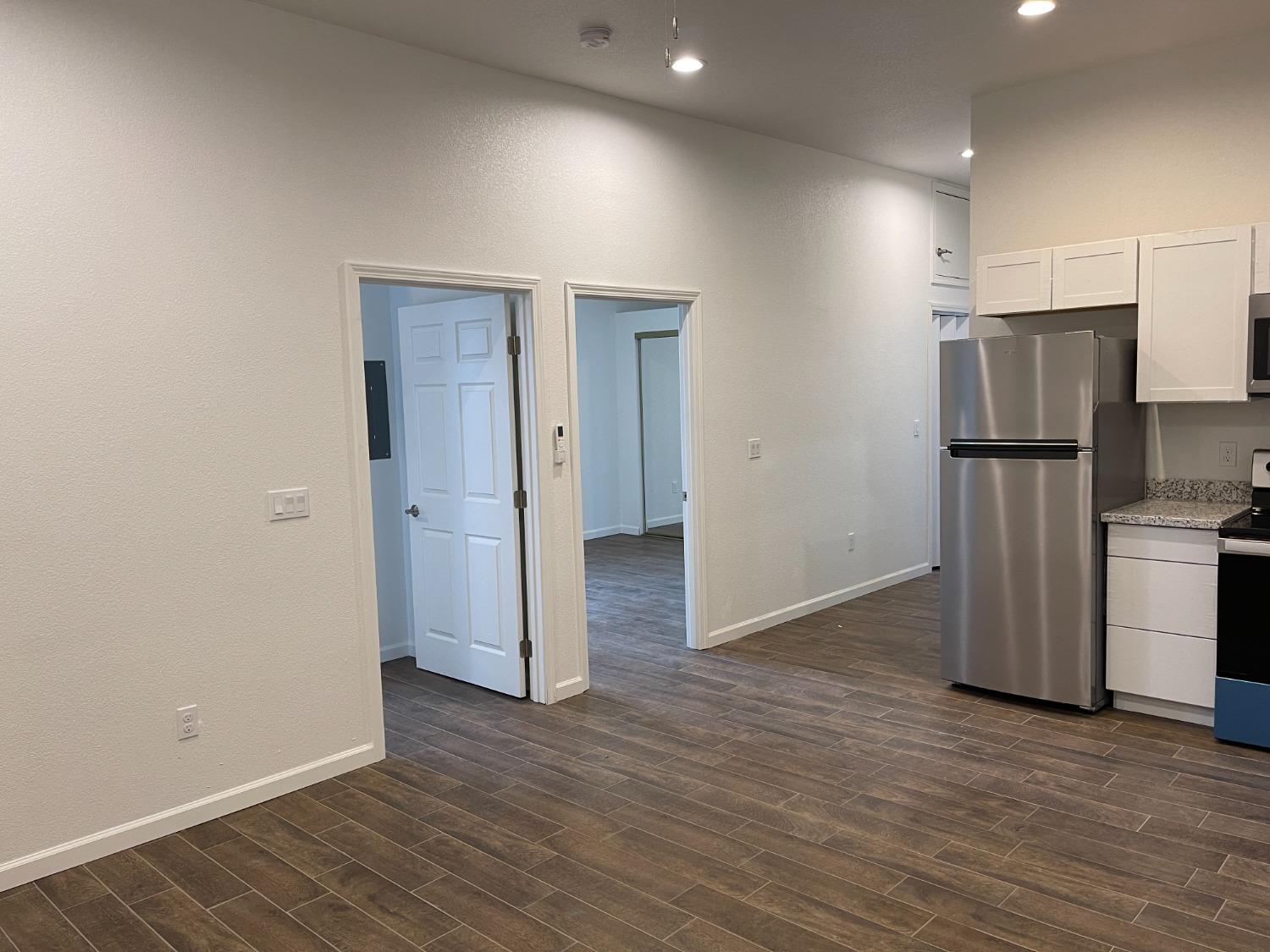 217 5th Street, Unit C Colusa, CA 95932 - Photo 2 of 13 an empty room with wooden floor and a refrigerator