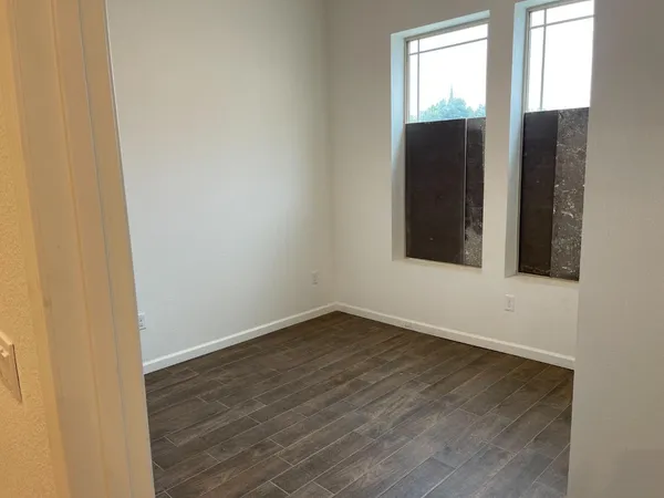 an empty room with wooden floor and windows