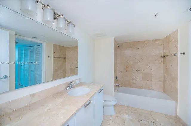 a bathroom with a granite countertop sink a toilet and bathtub