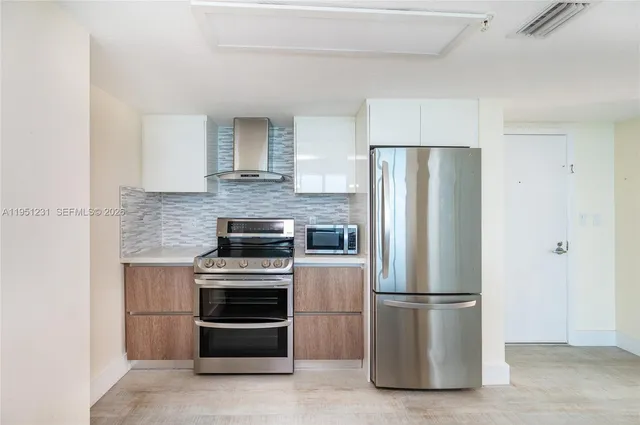 a kitchen with a stainless steel appliances and refrigerator