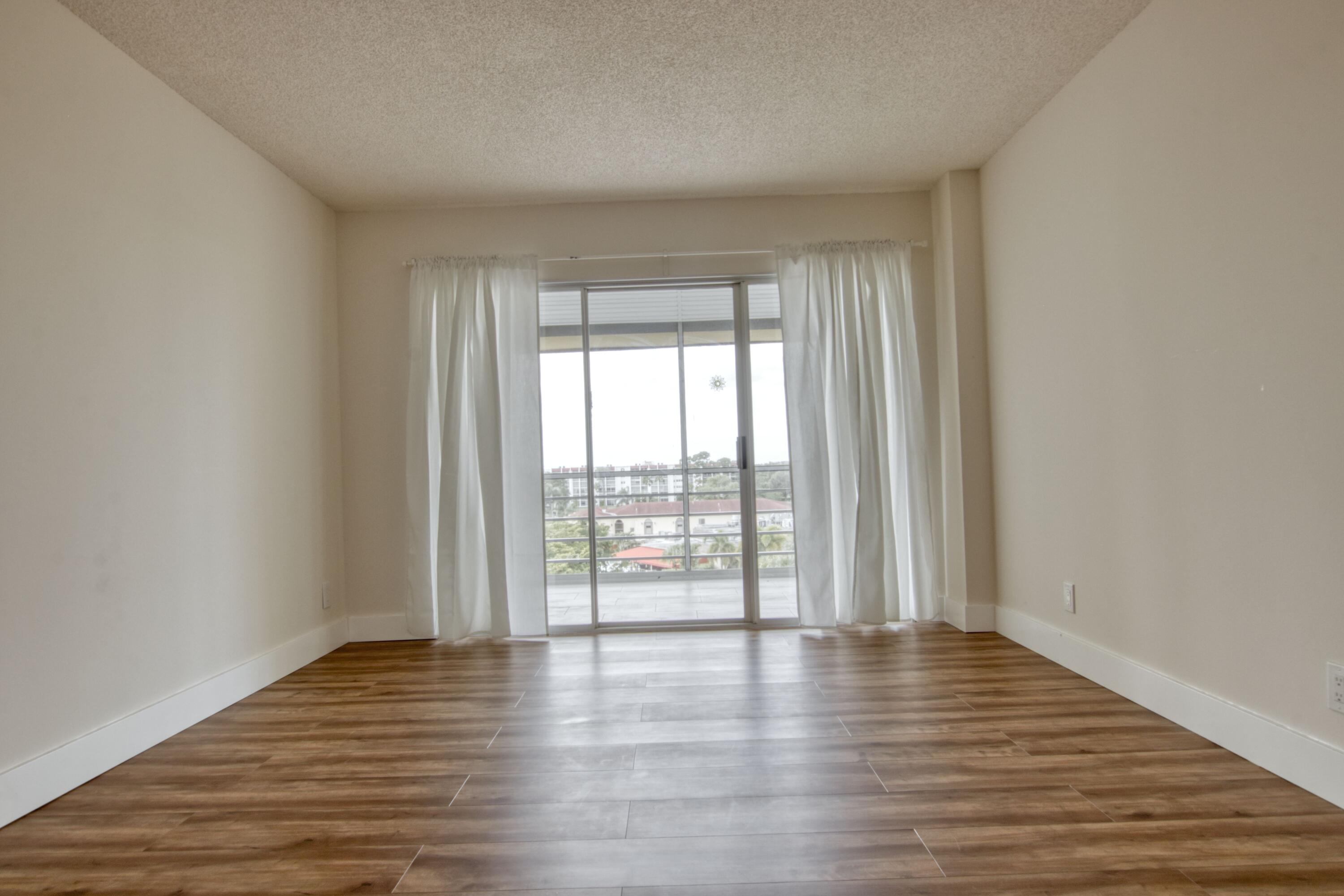 3590 Via Poinciana, Unit 614 Lake Worth, FL 33467 - Photo 16 of 20 wooden floor in an empty room with a window