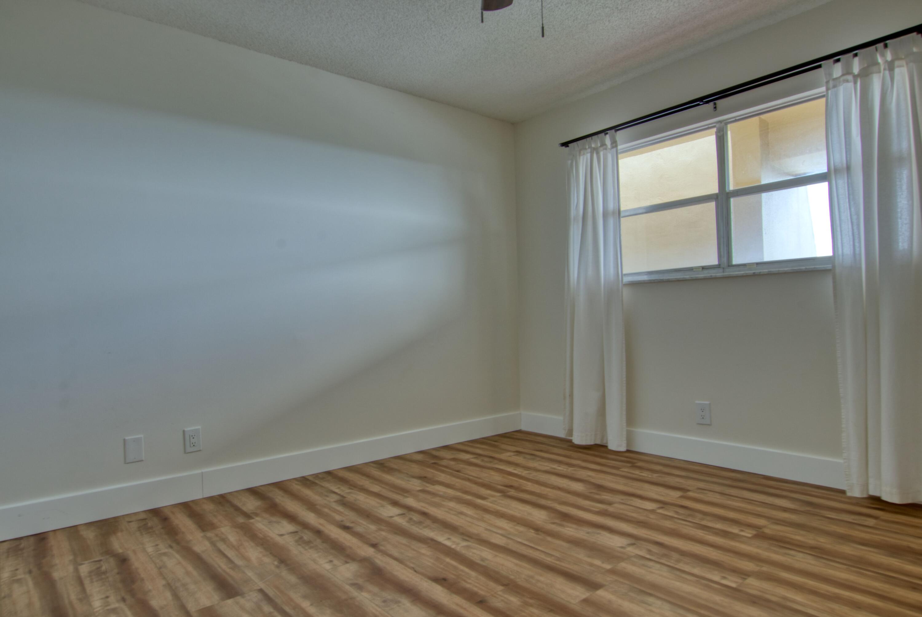 3590 Via Poinciana, Unit 614 Lake Worth, FL 33467 - Photo 18 of 20 an empty room with wooden floor and windows