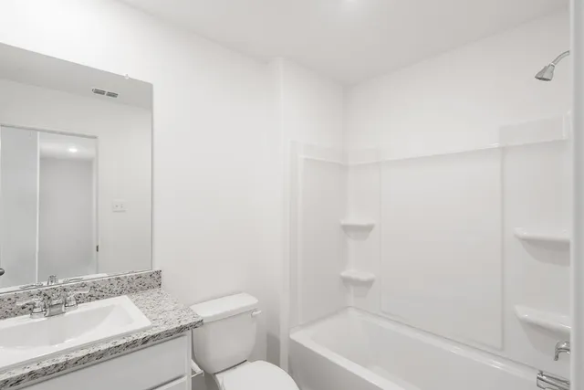 a bathroom with a granite countertop sink a toilet and shower