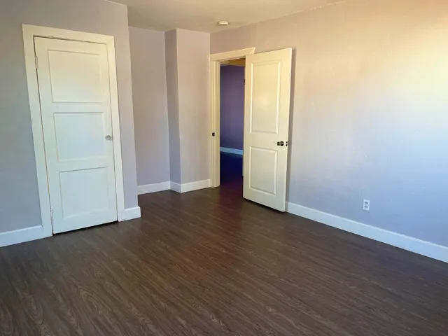an empty room with wooden floor and closet area