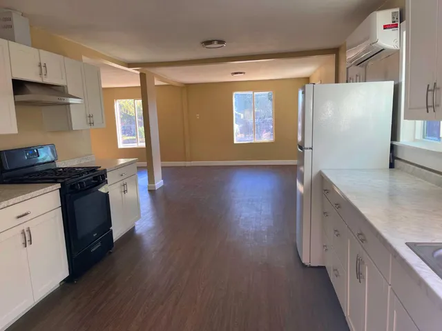 a kitchen with granite countertop a refrigerator and a stove top oven