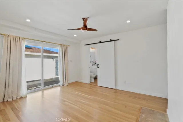 a view of an empty room with wooden floor and a ceiling fan