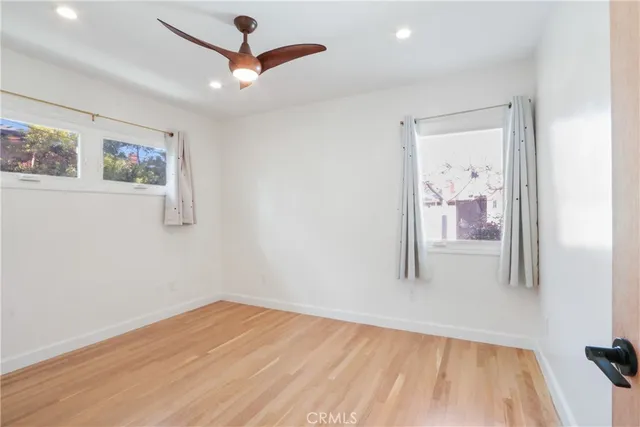 a view of empty room with wooden floor and fan