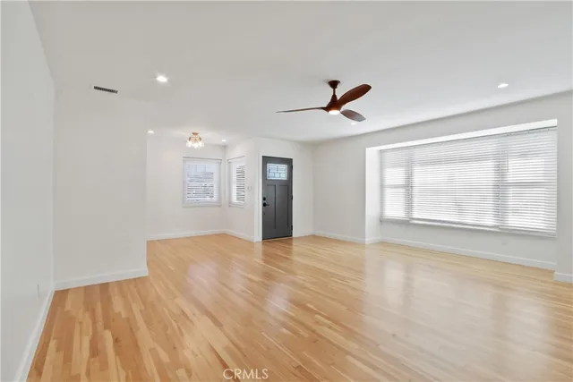 a view of an empty room with wooden floor and windows