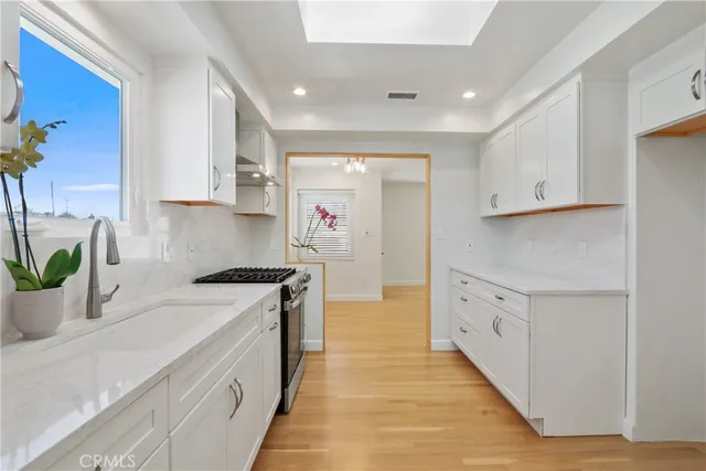 a kitchen with granite countertop a stove a sink and a refrigerator