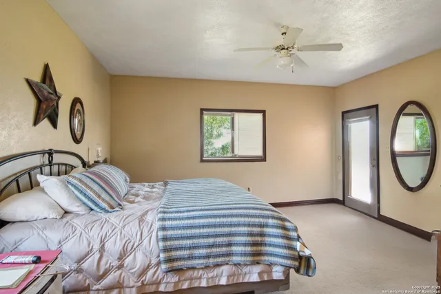 a bedroom with a bed a mirror and paintings on the dresser