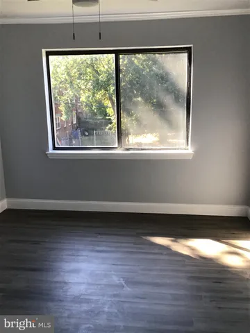 a view of a big room with wooden floor and a window