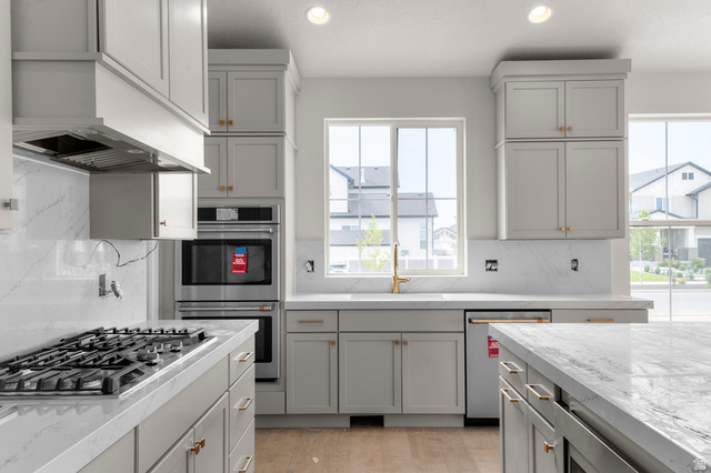 11718 South Halls Crk Road Draper, UT 84020 - Photo 17 of 28 Kitchen with gray cabinets, backsplash, stainless steel appliances, recessed lighting, and light stone countertops