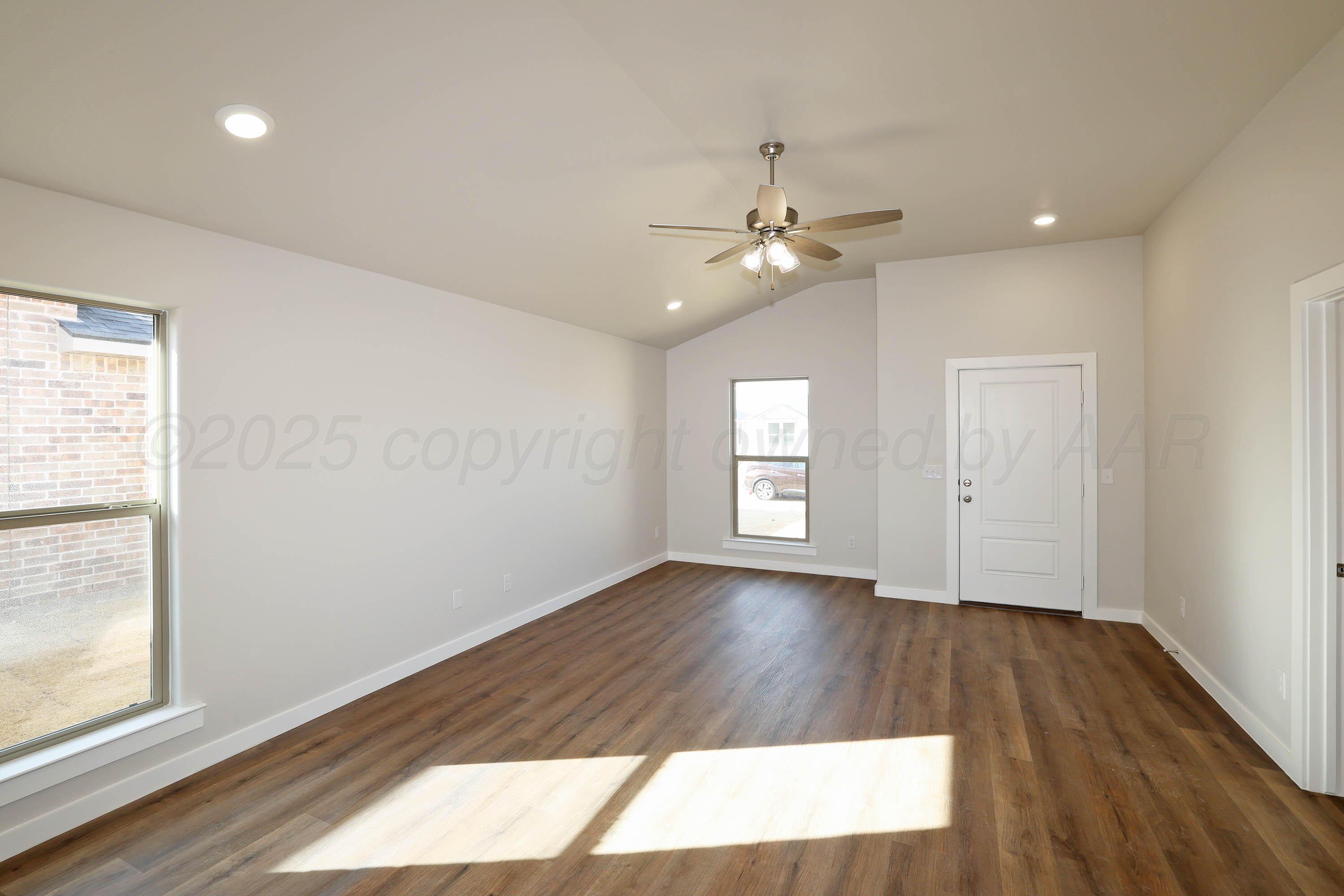 3003 Swenson Street Amarillo, TX 79124 - Photo 10 of 23 an empty room with wooden floor chandelier fan and windows