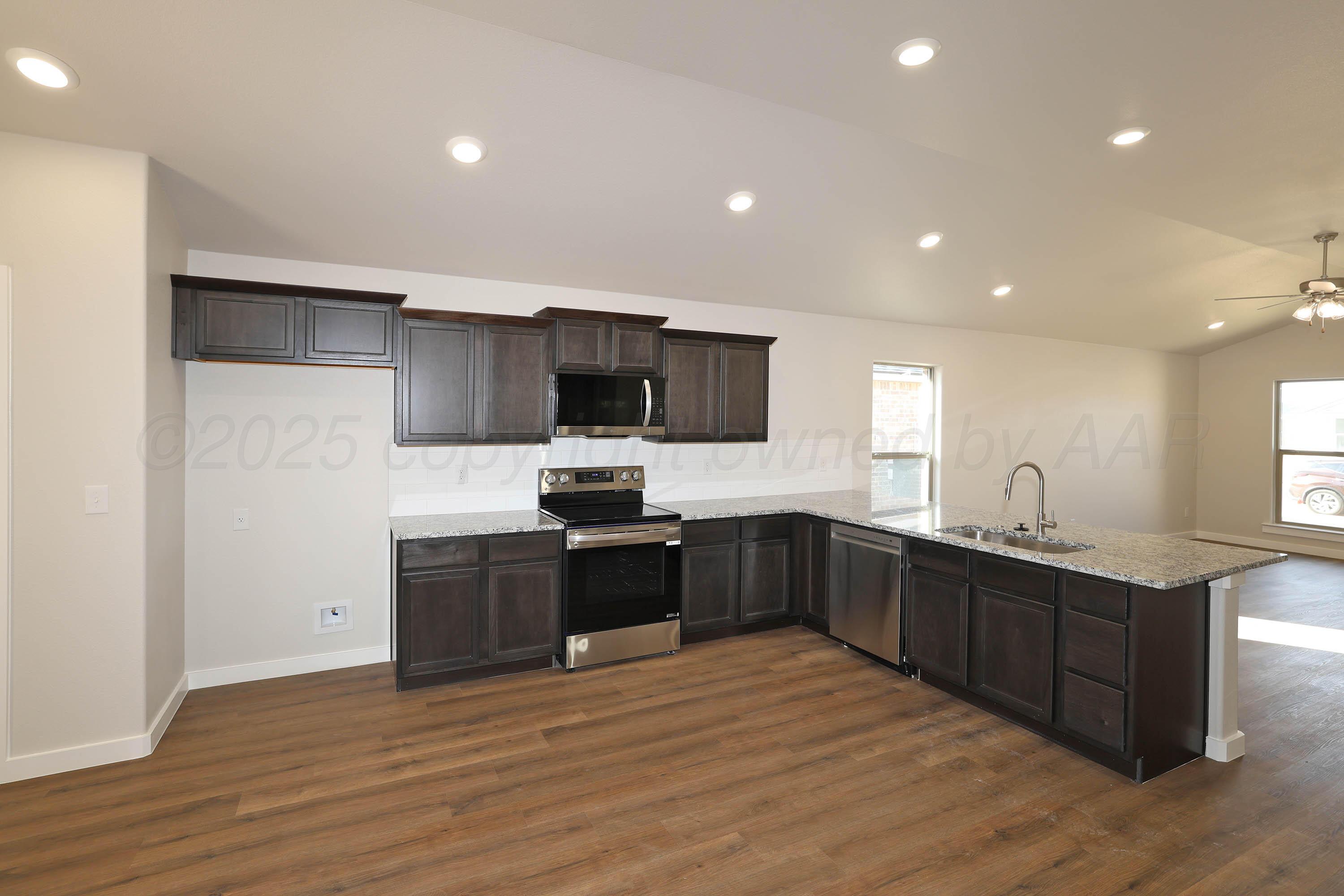 3003 Swenson Street Amarillo, TX 79124 - Photo 6 of 23 a large kitchen with stainless steel appliances kitchen island granite countertop a large counter top and wooden floors