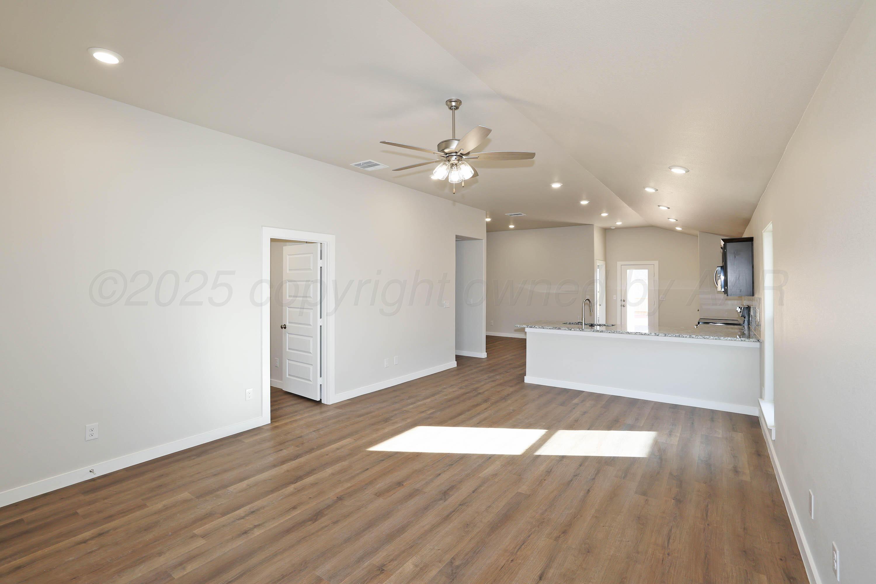 3003 Swenson Street Amarillo, TX 79124 - Photo 9 of 23 a view of an empty room with wooden floor and a ceiling fan