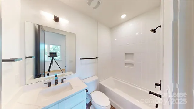 a bathroom with a sink vanity mirror bathtub and toilet