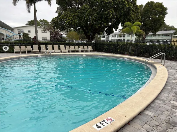 a view of a swimming pool with a lawn chairs under palm trees