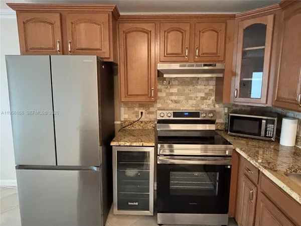 a kitchen with granite countertop a refrigerator stove and cabinets
