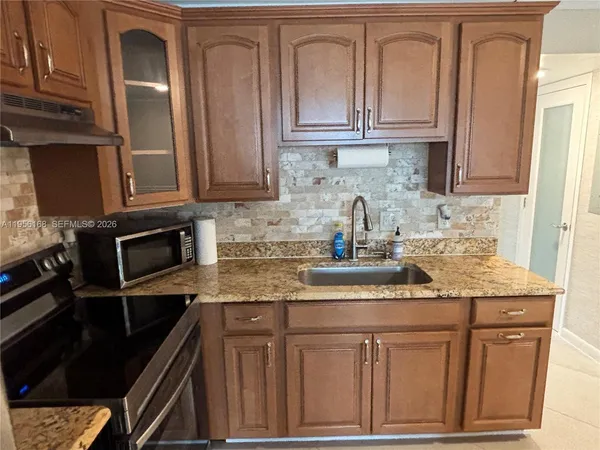 a kitchen with granite countertop a sink dishwasher stove and cabinets