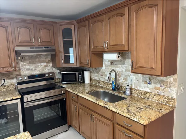 a kitchen with granite countertop a sink dishwasher stove and cabinets with wooden floor