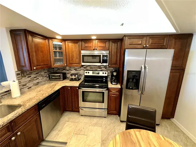a kitchen with stainless steel appliances granite countertop a refrigerator and a sink