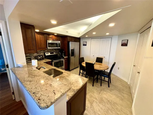a kitchen with stainless steel appliances granite countertop table chairs and a refrigerator