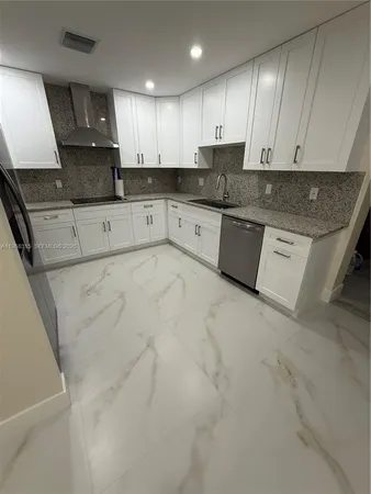 a large kitchen with granite countertop a stove a sink a microwave and cabinets