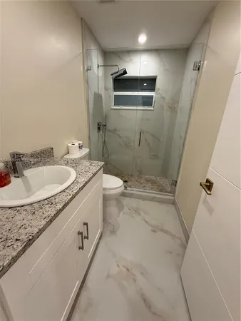 a spacious bathroom with a granite countertop sink a toilet and shower