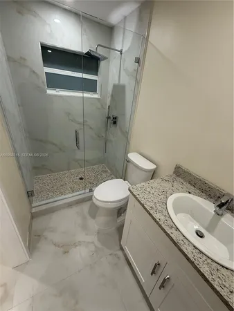 a bathroom with a granite countertop sink a toilet and shower