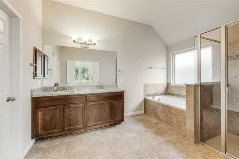 a spacious bathroom with a tub sink and mirror