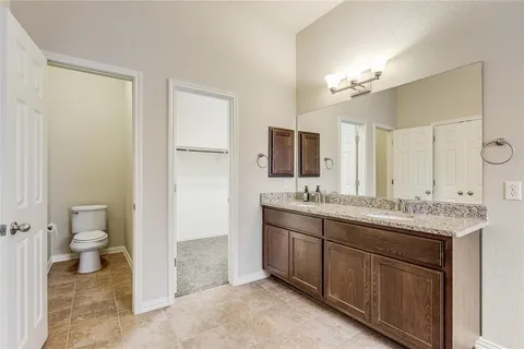 a bathroom with a granite countertop sink toilet and mirror